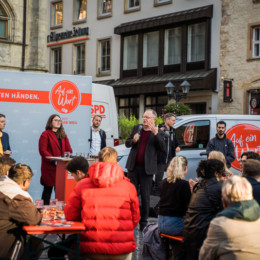 Hildesheimer Marktplatz mit Menschen die an Bierbänken sitzen und der Veranstaltung "Auf ein Wort mit Stephan Weil" zuhören.